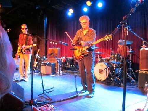 Guitarist Bill Million takes a turn on percussion, whacking the agogô, framed by Glenn Mercer and Stan Demeski.